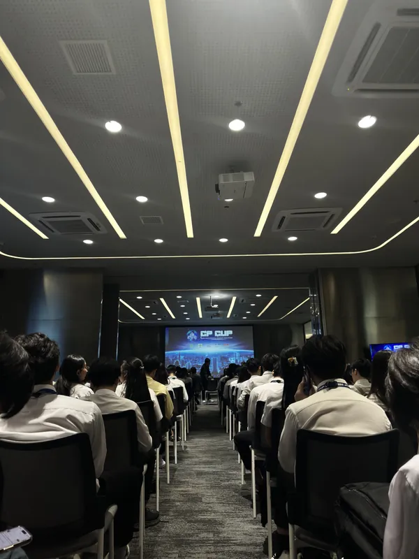 ห้องประชุมที่มีผู้ฟังนั่งเต็ม มองไปยังจอด้านหน้าที่แสดงโลโก้ CP CUP